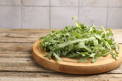 Photo of Fresh ripe green arugula leaves on wooden table, closeup. Space for text