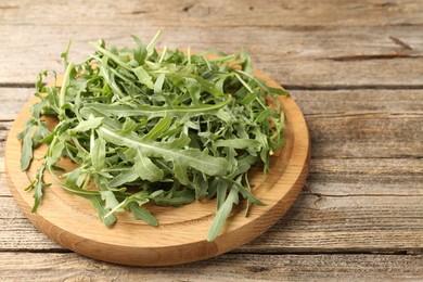 Photo of Fresh ripe green arugula leaves on wooden table, closeup