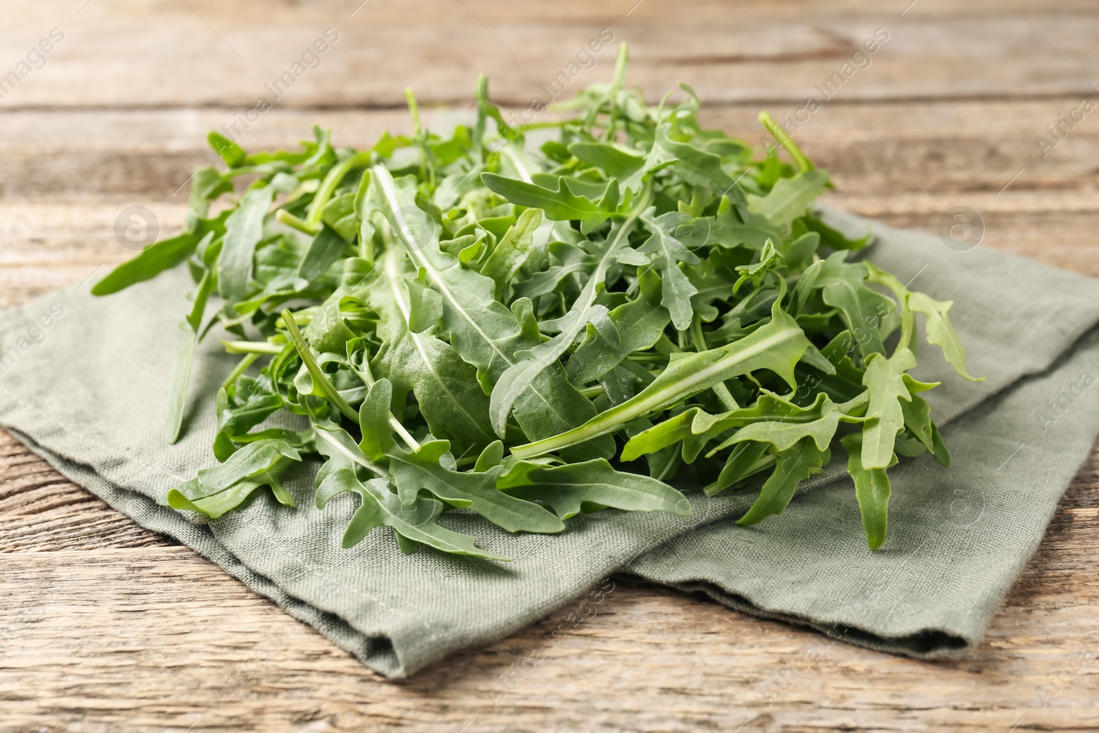 Fresh ripe green arugula leaves on wooden table, closeup Photo of Fresh ripe green arugula leaves on wooden table, closeup