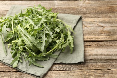 Photo of Fresh ripe green arugula leaves on wooden table, closeup. Space for text