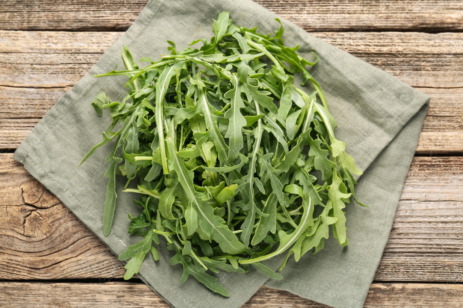 Fresh ripe green arugula leaves on wooden table, top view Photo of Fresh ripe green arugula leaves on wooden table, top view