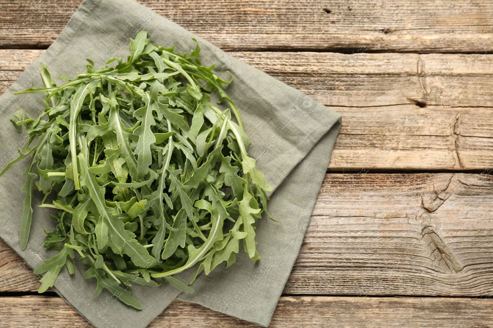 Photo of Fresh ripe green arugula leaves on wooden table, top view. Space for text