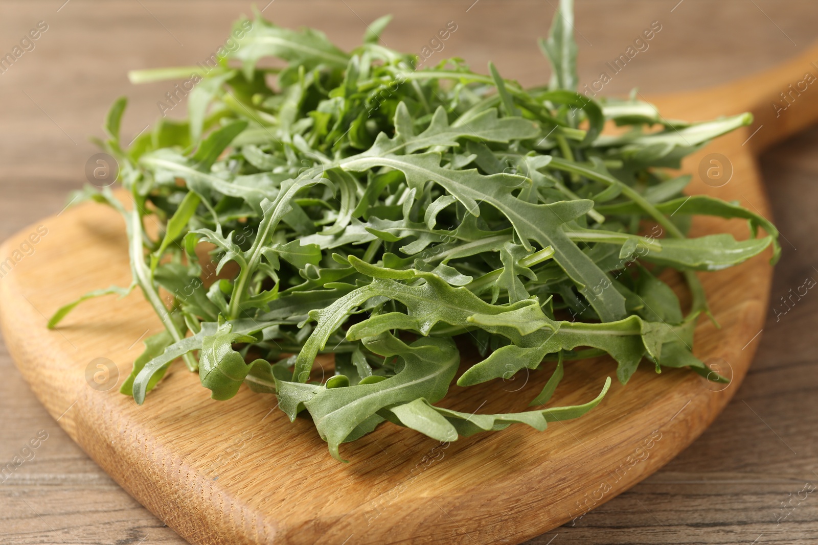 Fresh ripe green arugula leaves on wooden table, closeup Photo of Fresh ripe green arugula leaves on wooden table, closeup