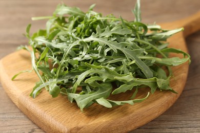 Photo of Fresh ripe green arugula leaves on wooden table, closeup