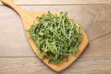 Photo of Fresh ripe green arugula leaves on wooden table, top view