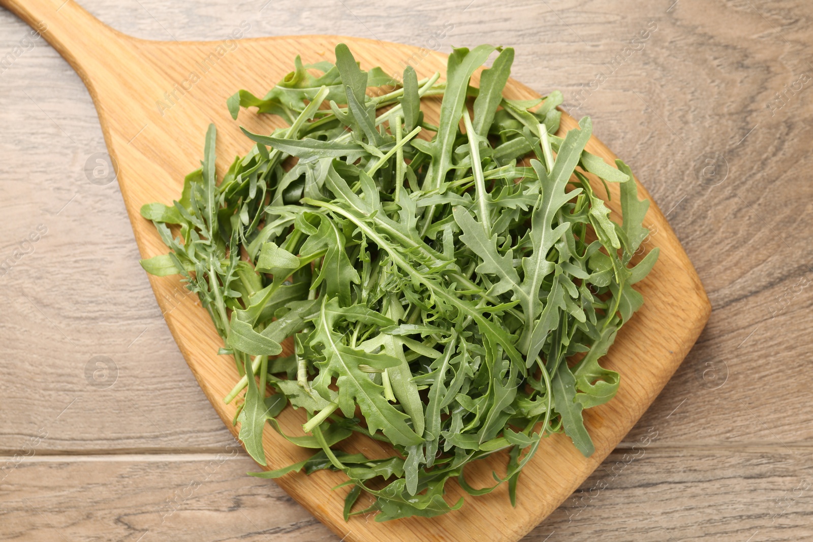 Fresh ripe green arugula leaves on wooden table, top view Photo of Fresh ripe green arugula leaves on wooden table, top view