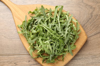 Photo of Fresh ripe green arugula leaves on wooden table, top view
