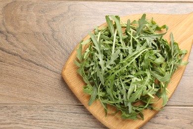Photo of Fresh ripe green arugula leaves on wooden table, top view. Space for text