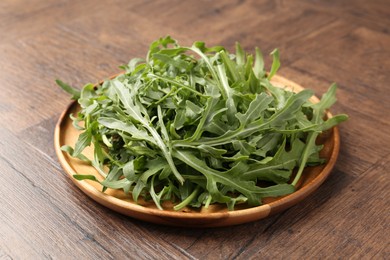 Photo of Fresh ripe green arugula leaves on wooden table, closeup