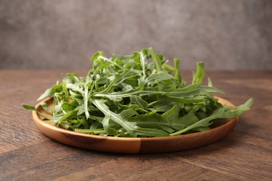 Photo of Fresh ripe green arugula leaves on wooden table, closeup