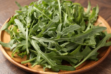 Photo of Fresh ripe green arugula leaves on wooden table, closeup