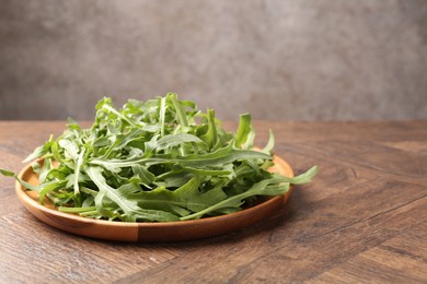 Photo of Fresh ripe green arugula leaves on wooden table, closeup. Space for text