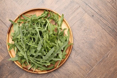 Photo of Fresh ripe green arugula leaves on wooden table, top view. Space for text
