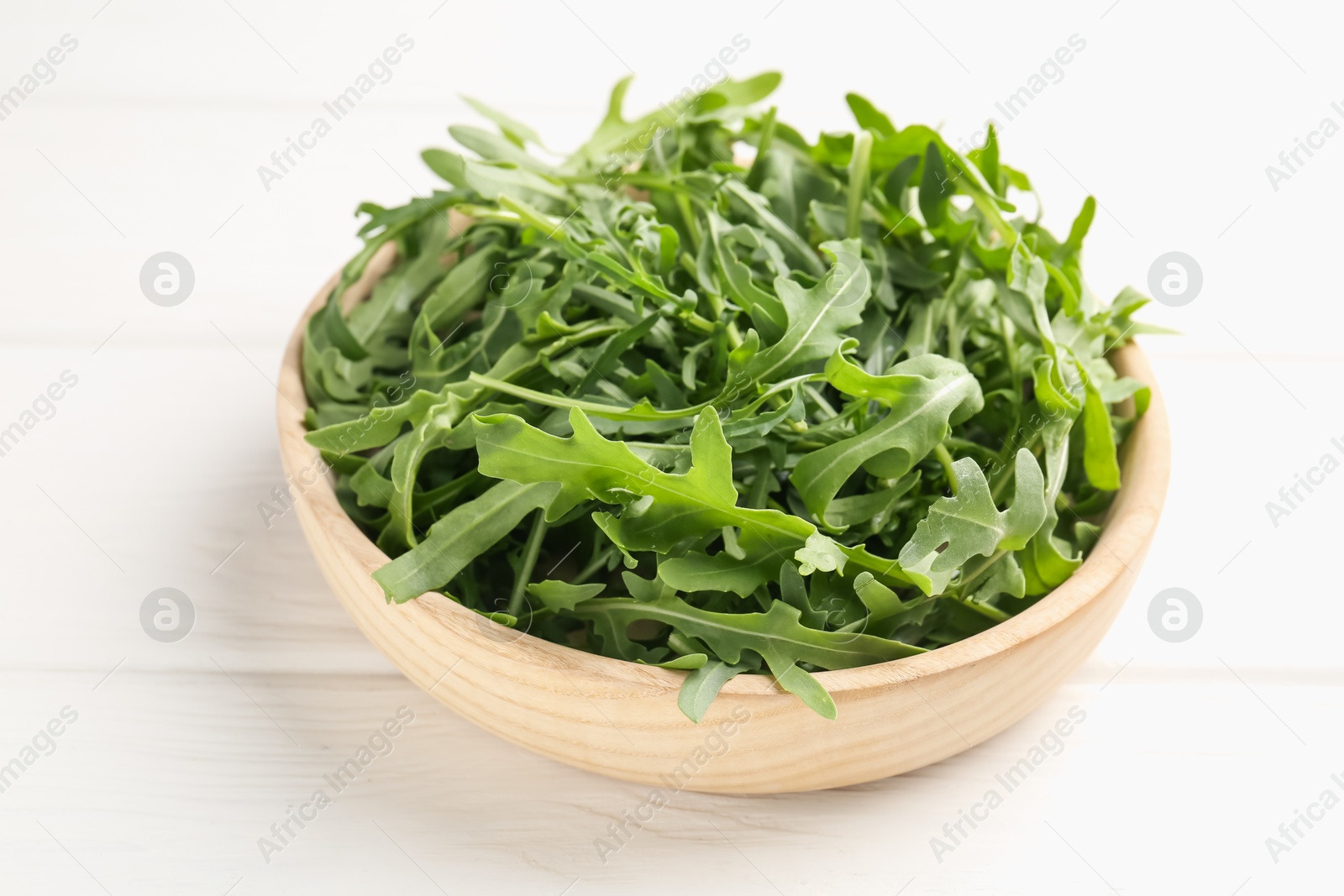 Fresh ripe green arugula leaves on white wooden table, closeup Photo of Fresh ripe green arugula leaves on white wooden table, closeup
