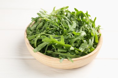 Photo of Fresh ripe green arugula leaves on white wooden table, closeup