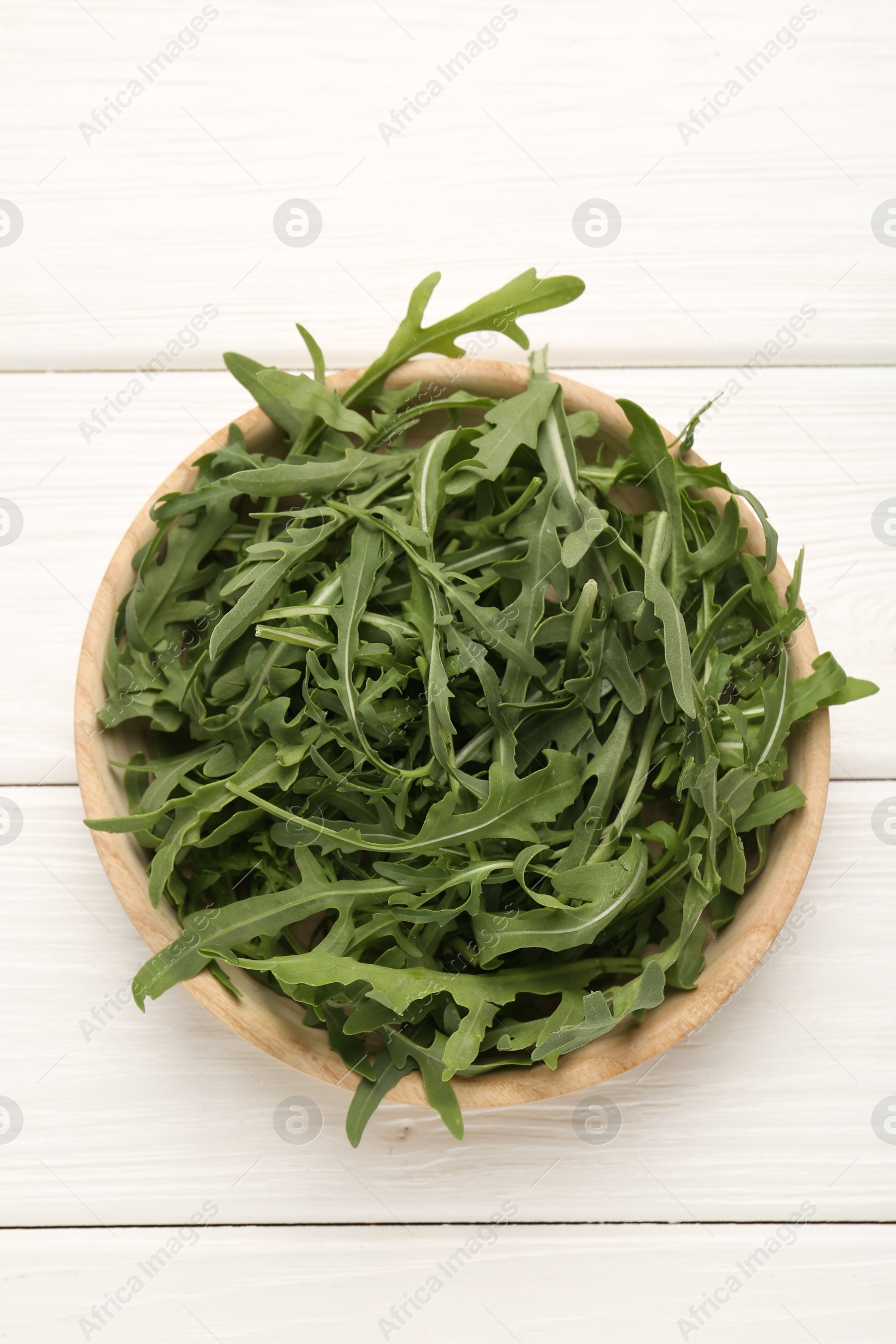Fresh ripe green arugula leaves on white wooden table, top view Photo of Fresh ripe green arugula leaves on white wooden table, top view