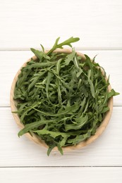 Photo of Fresh ripe green arugula leaves on white wooden table, top view