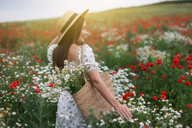 Photo of Woman in hat with bag of chamomile flowers in wildflower meadow
