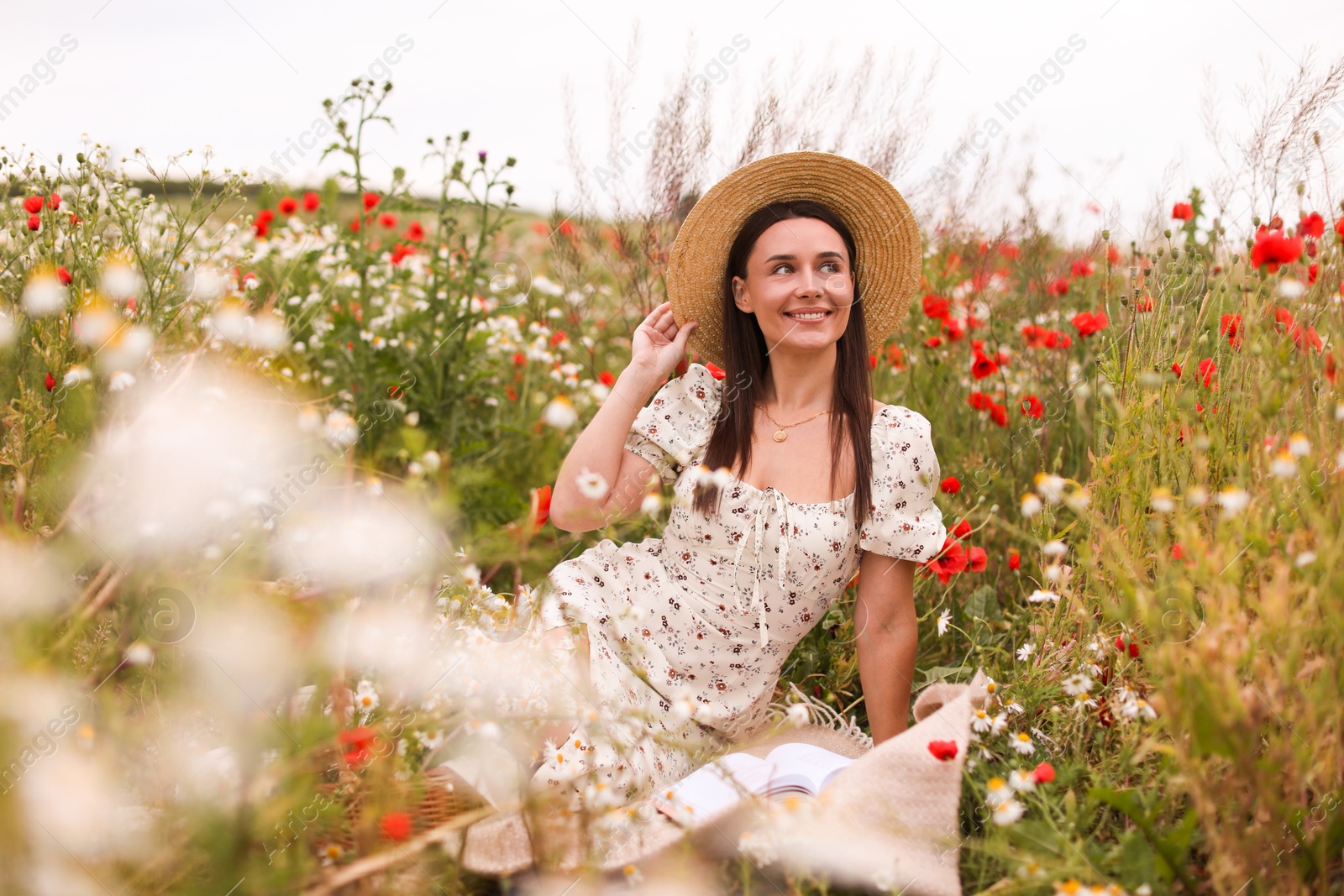 Photo of Smiling woman in hat enjoying nature in wildflower meadow