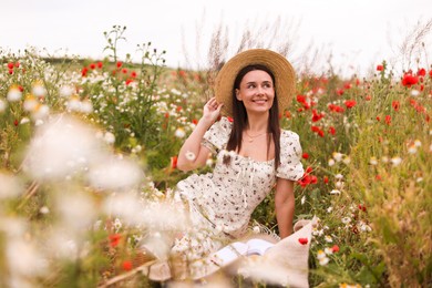 Photo of Smiling woman in hat enjoying nature in wildflower meadow