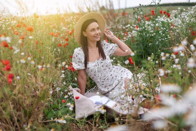 Photo of Smiling woman in hat enjoying nature in wildflower meadow