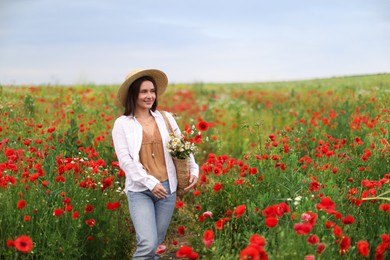 Photo of Smiling woman in hat with bag of wildflowers among poppy flowers in meadow