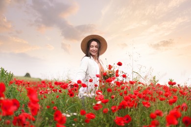Photo of Smiling woman in hat picking wildflowers in meadow