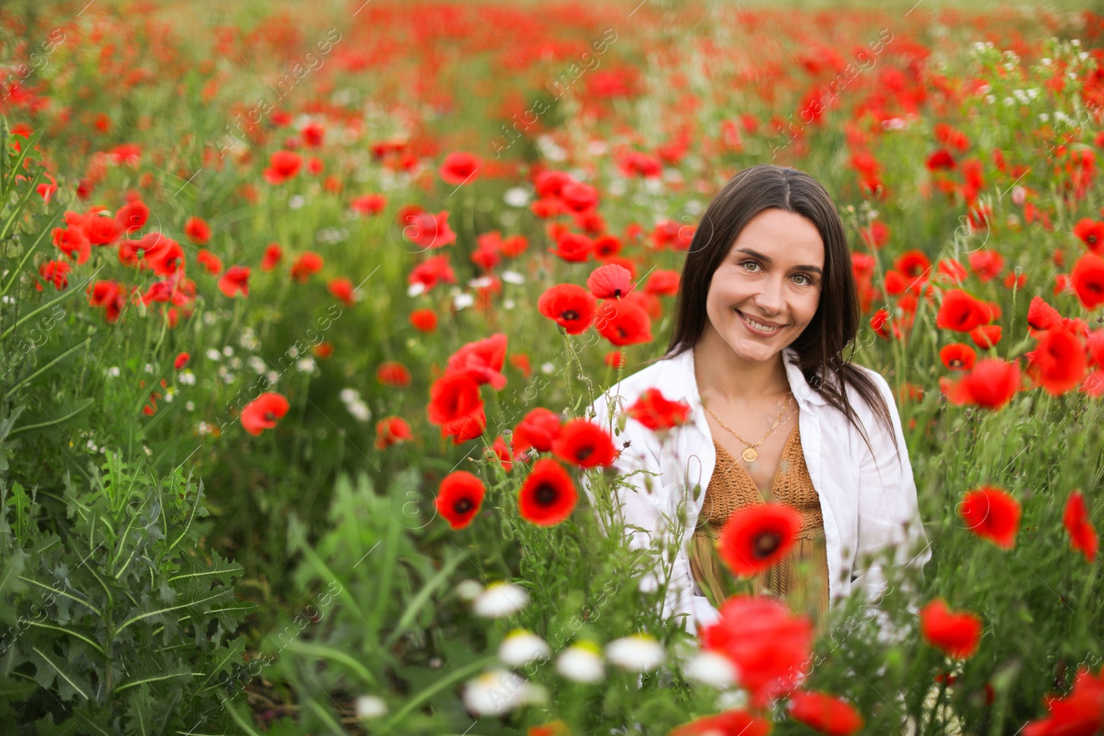 Smiling woman among red poppy flowers in wildflower meadow Photo of Smiling woman among red poppy flowers in wildflower meadow