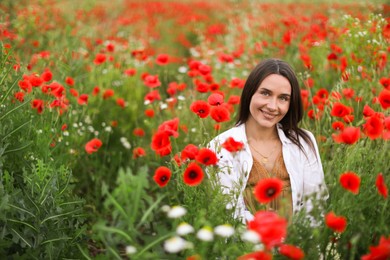 Photo of Smiling woman among red poppy flowers in wildflower meadow