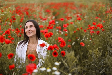 Photo of Smiling woman among red poppy flowers in wildflower meadow