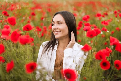Photo of Smiling woman among red poppy flowers in wildflower meadow