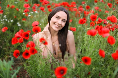 Photo of Portrait of smiling woman among red poppy flowers in wildflower meadow