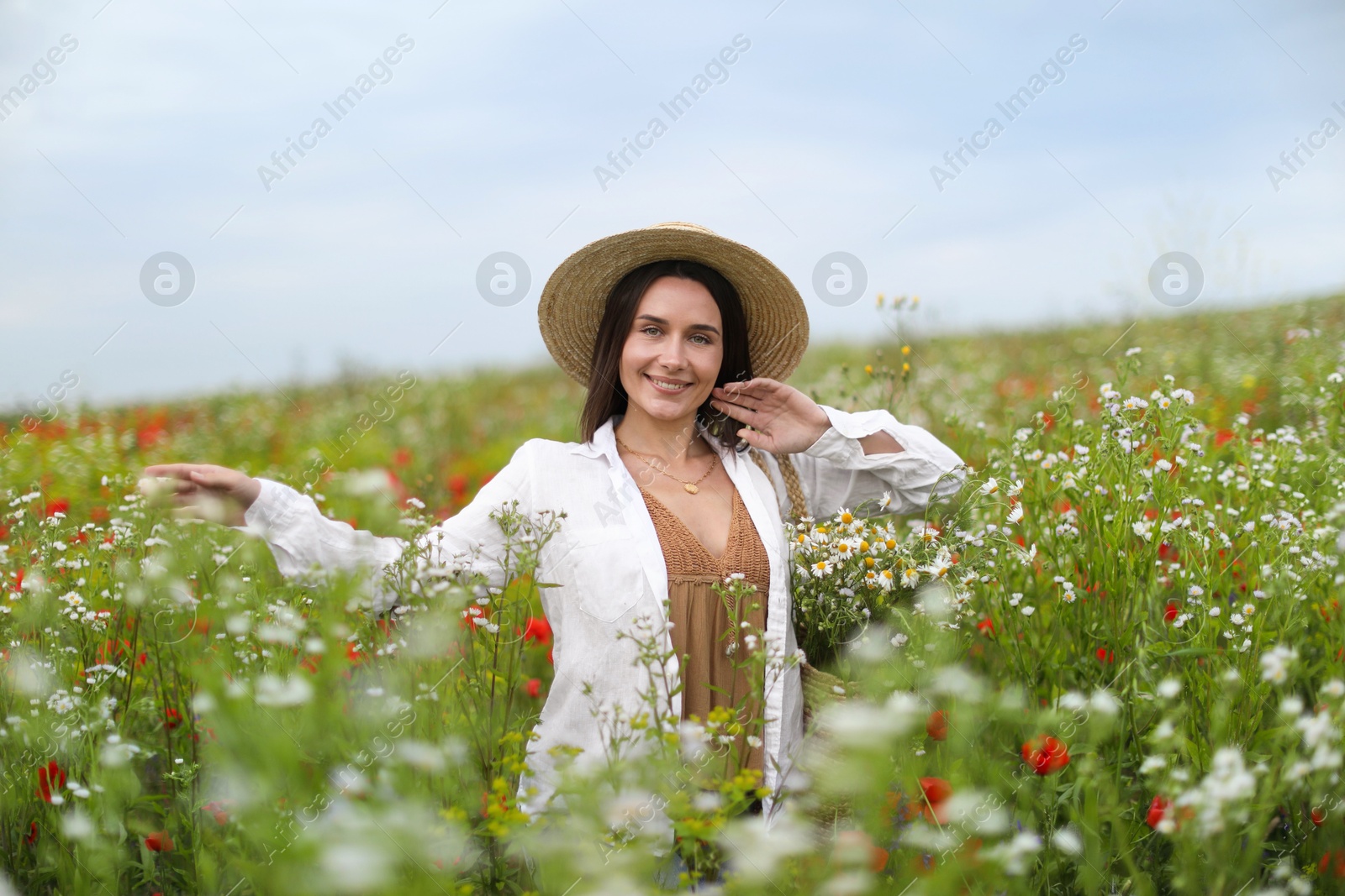 Smiling woman in hat walking in wildflower meadow Photo of Smiling woman in hat walking in wildflower meadow