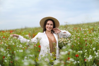 Photo of Smiling woman in hat walking in wildflower meadow