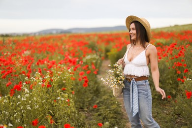 Photo of Smiling woman in hat with bag of chamomile flowers in wildflower meadow