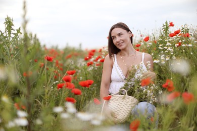 Photo of Smiling woman in hat with bag of chamomile flowers in wildflower meadow