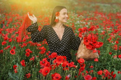 Photo of Smiling woman with bag and handkerchief among red poppy flowers in morning wildflower meadow