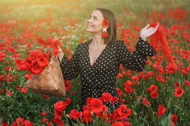 Photo of Smiling woman with bag and handkerchief among red poppy flowers in morning wildflower meadow