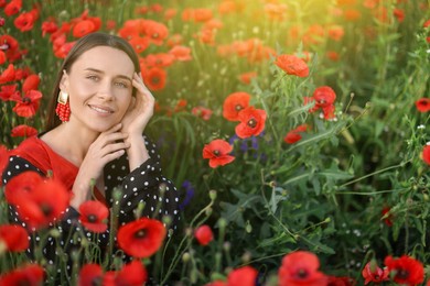 Photo of Portrait of smiling woman among red poppy flowers in morning wildflower meadow