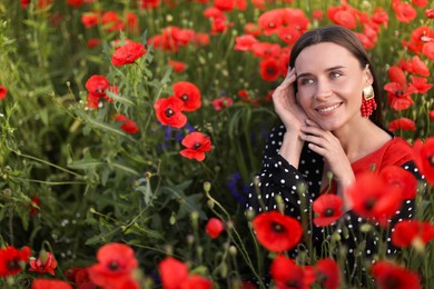 Photo of Smiling woman among red poppy flowers in morning wildflower meadow