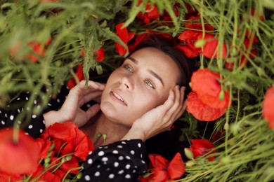 Photo of Beautiful woman among red poppy flowers in wildflower meadow