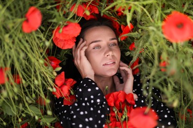 Photo of Beautiful woman among red poppy flowers in wildflower meadow, above view