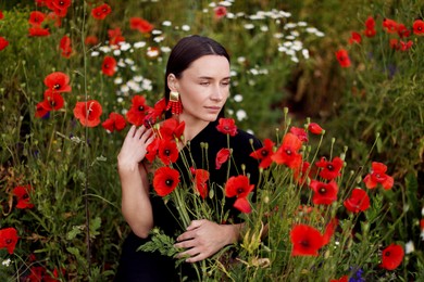 Photo of Beautiful woman among red poppy flowers in wildflower meadow