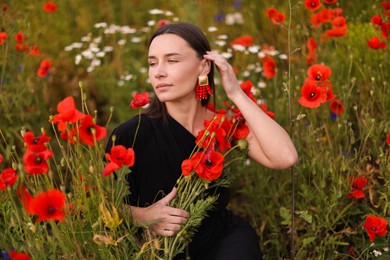 Photo of Beautiful woman among red poppy flowers in wildflower meadow