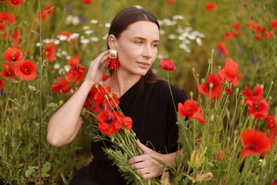 Photo of Beautiful woman among red poppy flowers in wildflower meadow