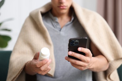 Photo of Man with pills having online consultation with doctor via smartphone at home, closeup