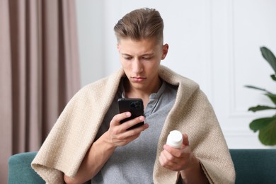 Photo of Man with pills having online consultation with doctor via smartphone at home