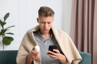 Photo of Man with pills having online consultation with doctor via smartphone at home