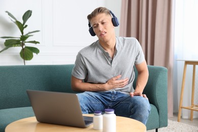 Photo of Man in headphones having online consultation with doctor via laptop at home