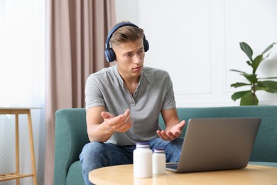Photo of Man in headphones having online consultation with doctor via laptop at home